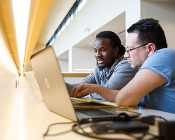 two students working on a computer in the library